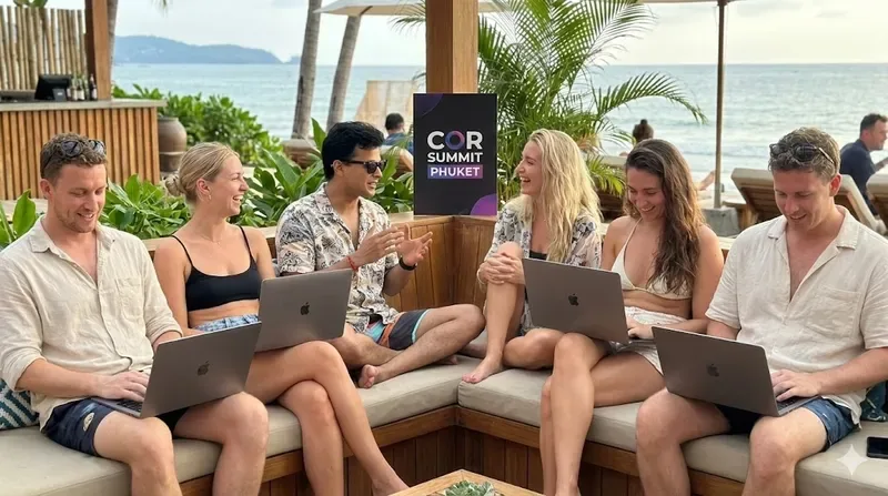 The COR team working on laptops on outdoor sofas among palms in Phuket