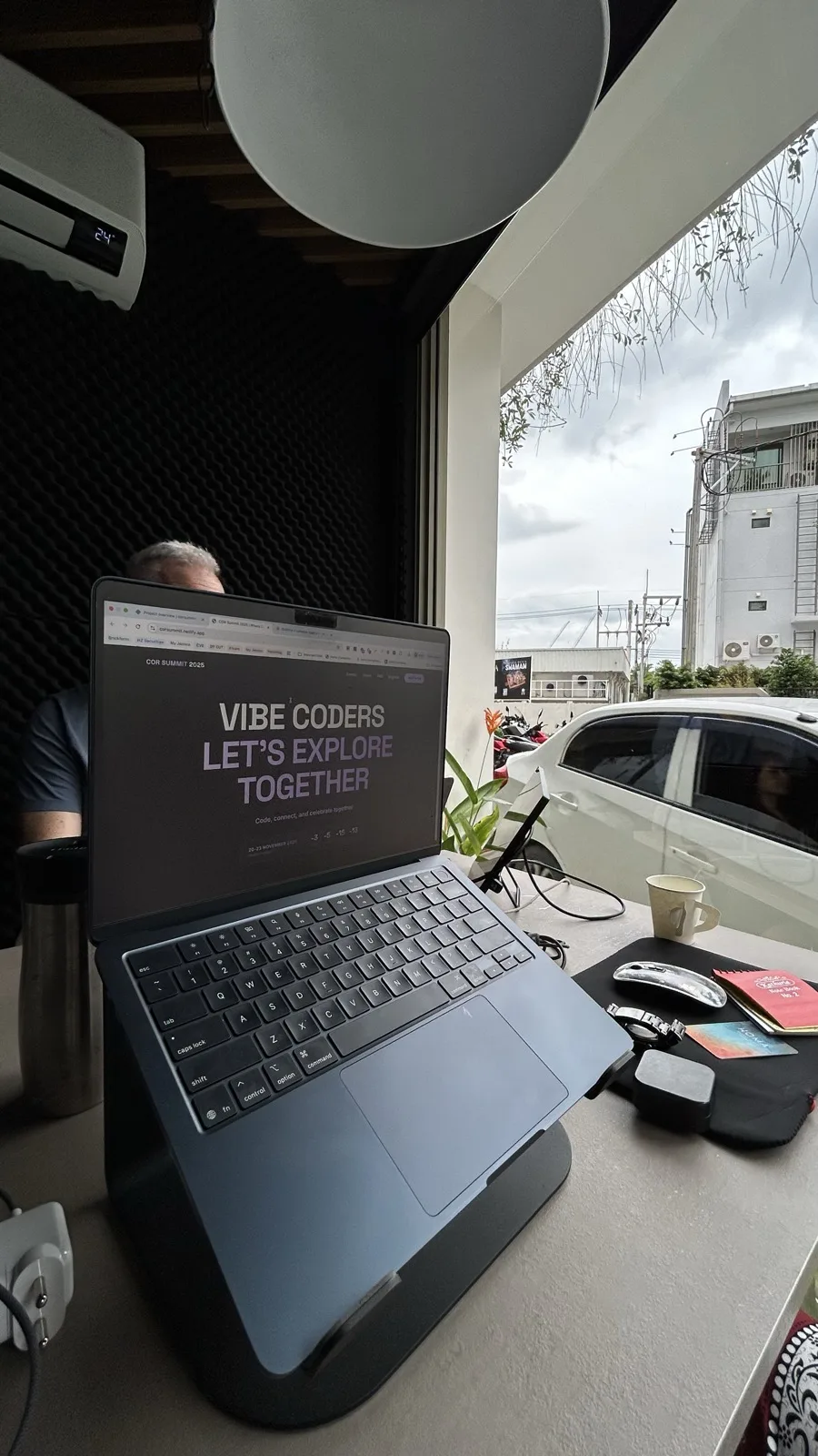A laptop open on a lap in transit, with a coding sticker on the lid